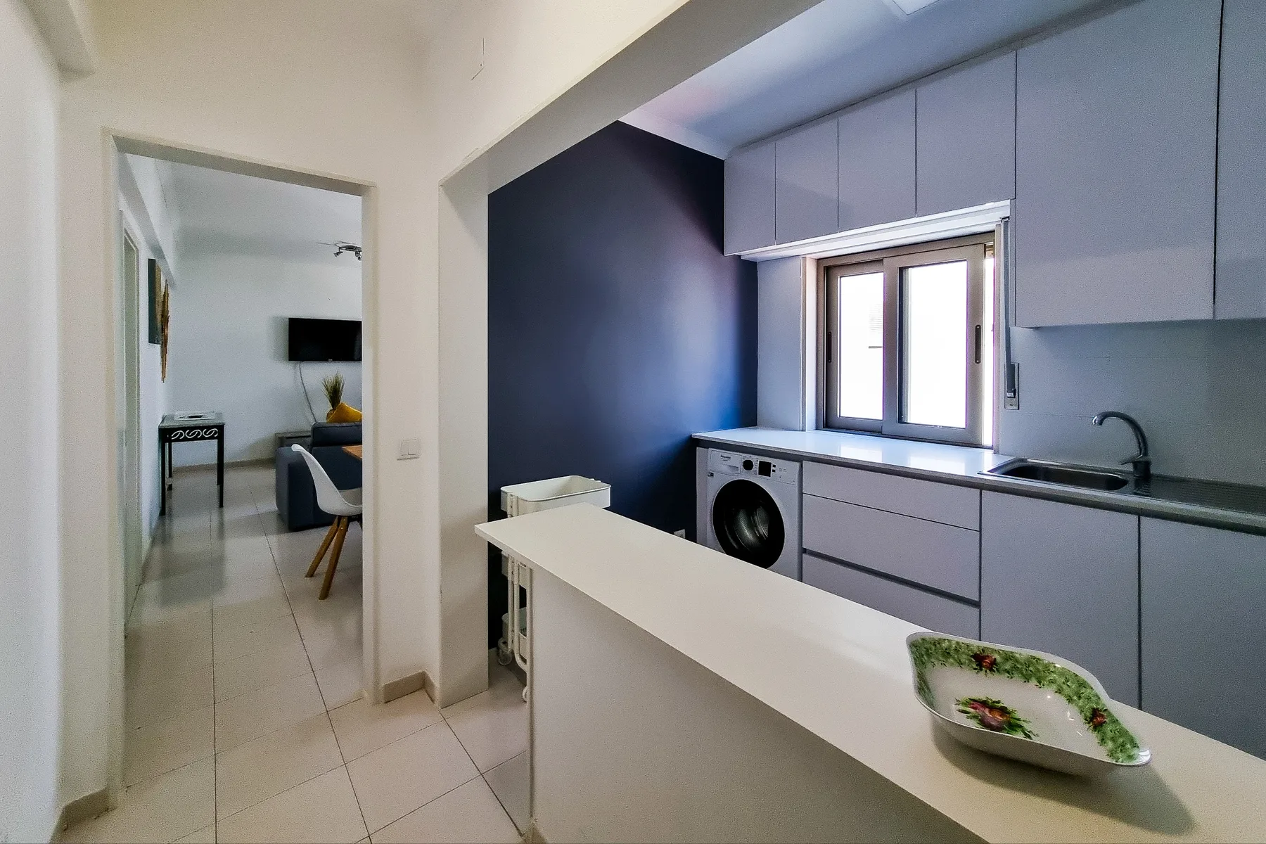 A compact kitchen with gray cabinets, a sink, and a breakfast counter.