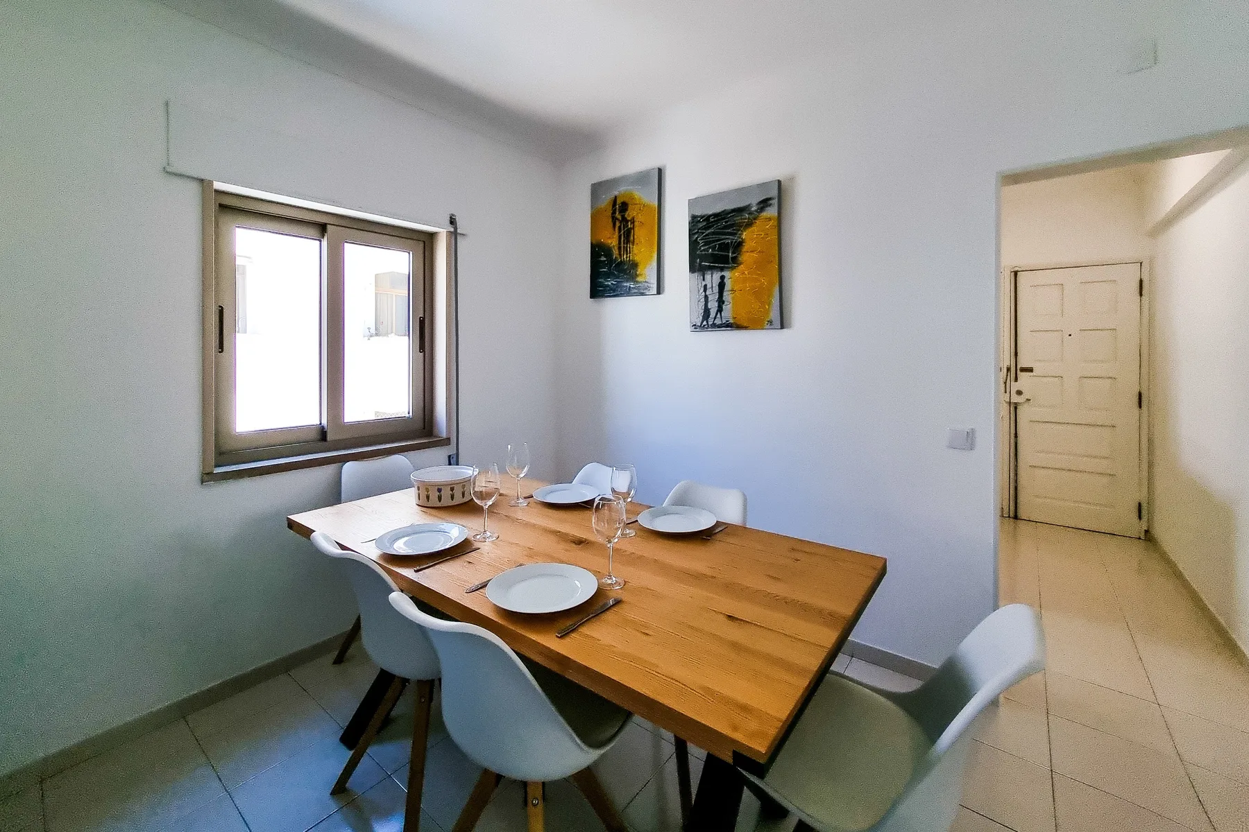 Comedor con una mesa de madera puesta con platos y vasos.