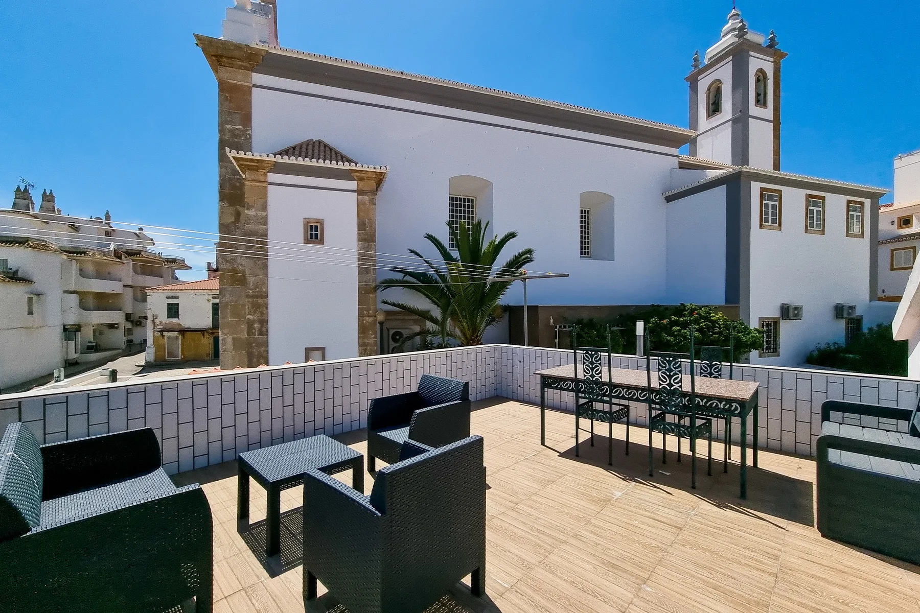 Una terraza en la azotea con asientos al aire libre da a un gran edificio blanco.