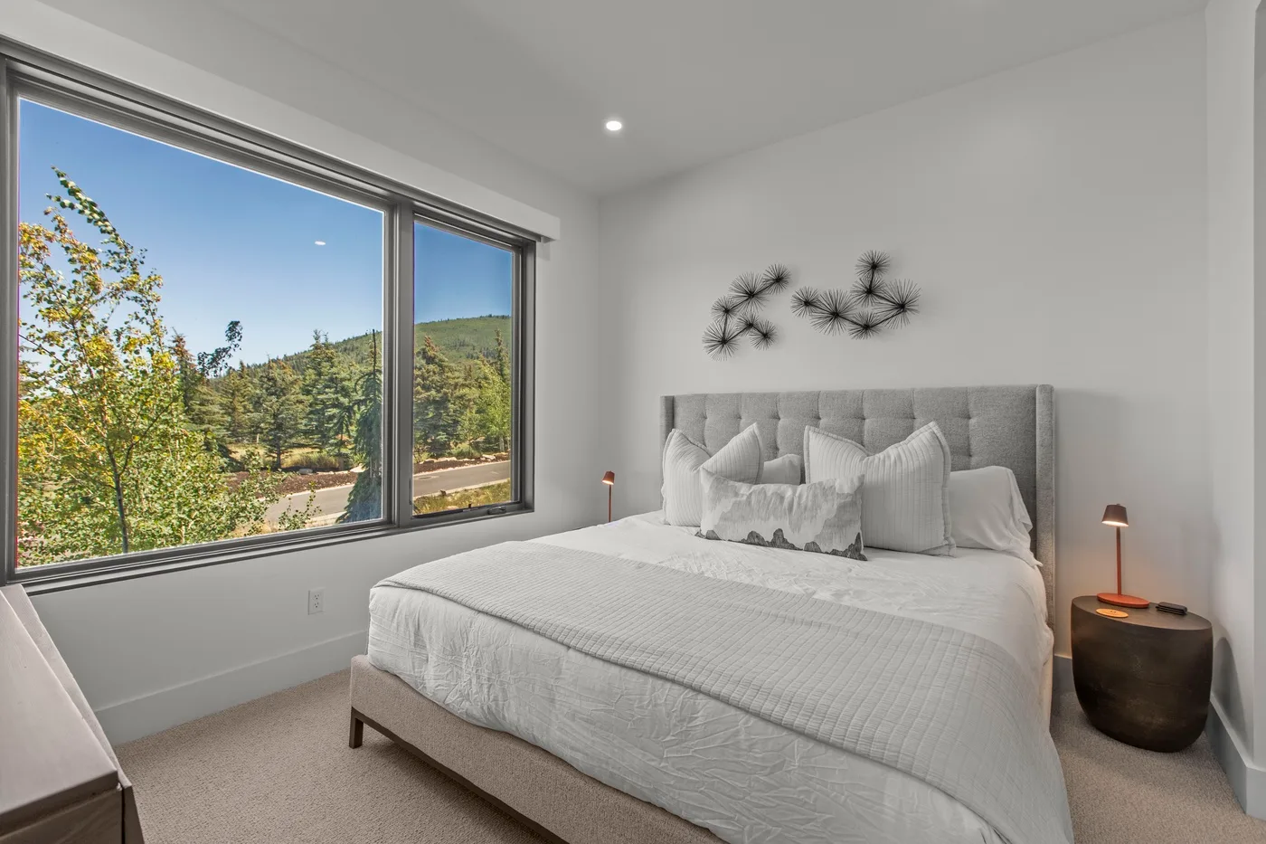 Un dormitorio luminoso con una cama tendida junto a una ventana grande.