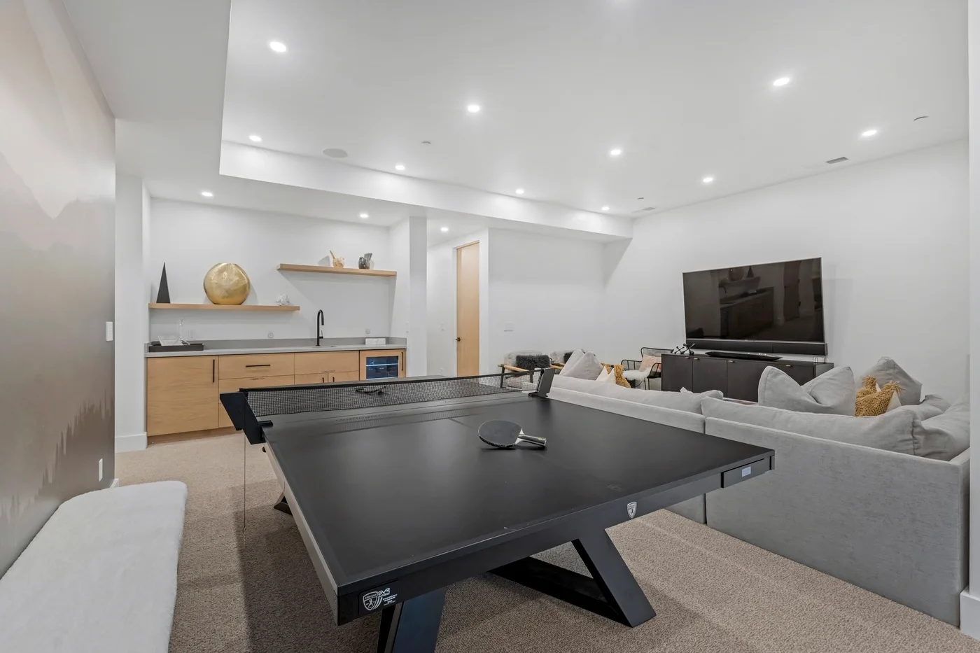 Una sala de estar luminosa con una mesa de ping-pong grande frente a la zona de estar.