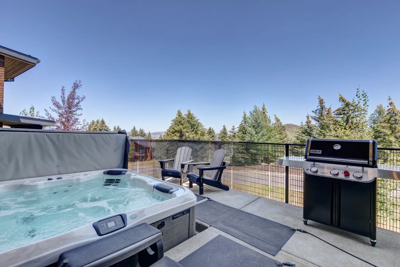 Un patio exterior cuenta con una bañera de hidromasaje burbujeante y una parrilla.