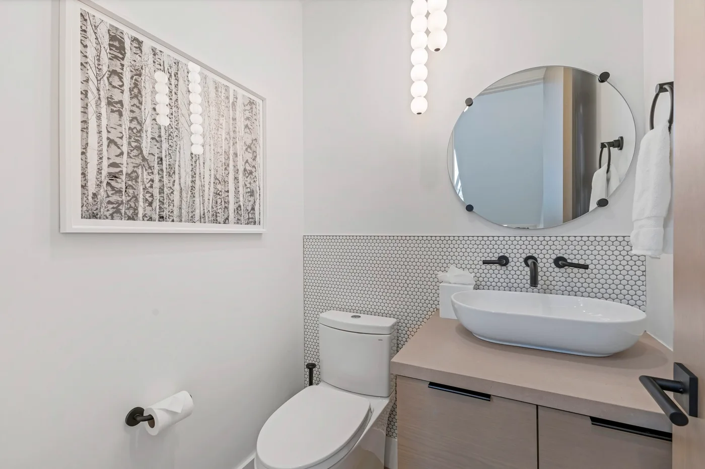 Un baño con lavabo, inodoro y espejo redondo.