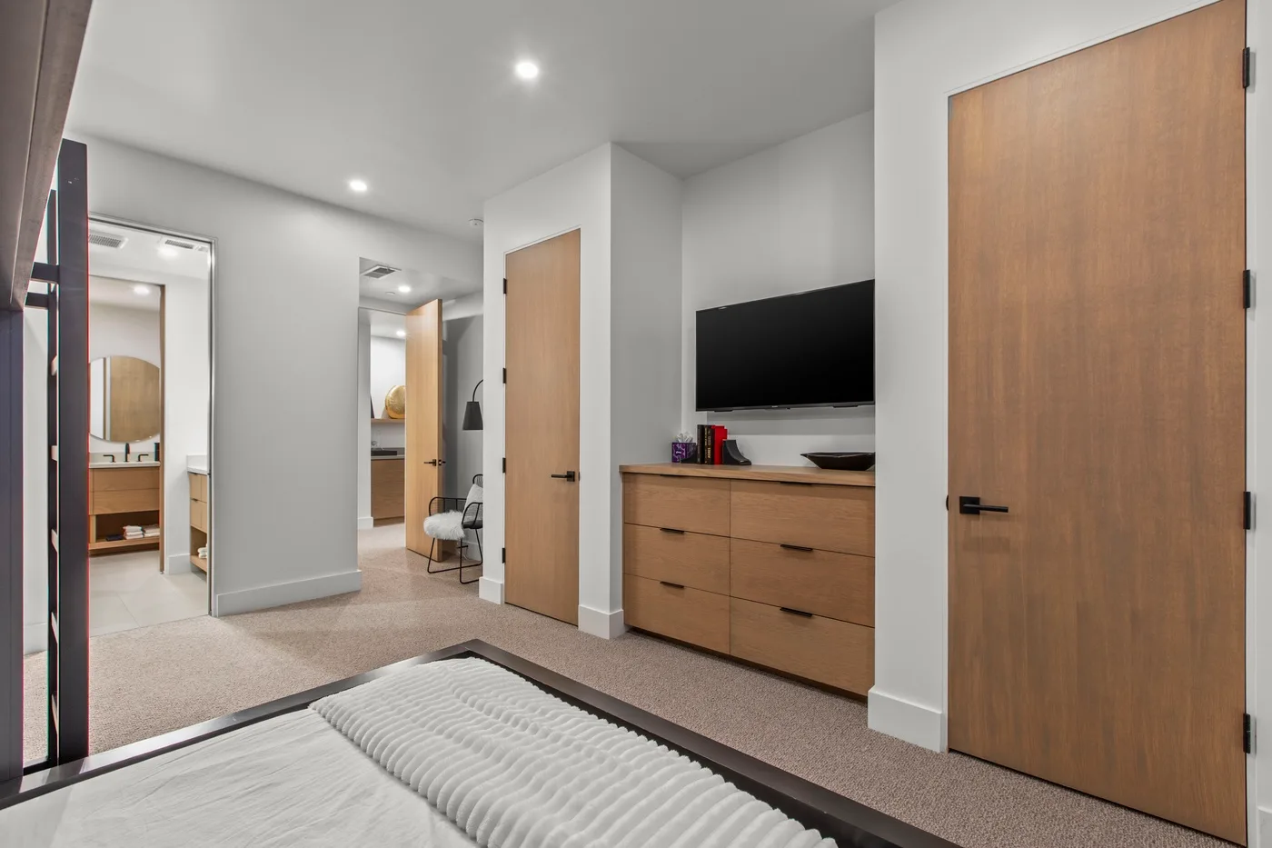Un dormitorio con una cama, una cómoda de madera y un televisor en la pared.