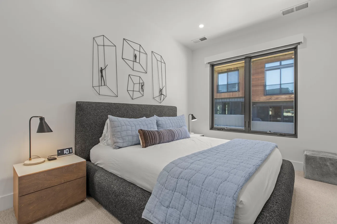 Un dormitorio con una cama bien tendida y ventanas amplias.