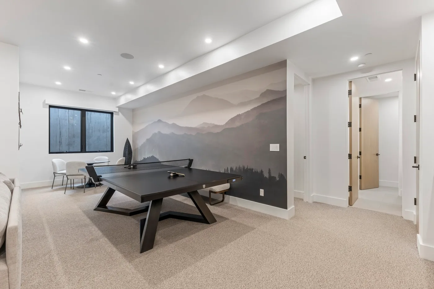 Una sala de recreación con mesa de billar, asientos y un mural de montañas.