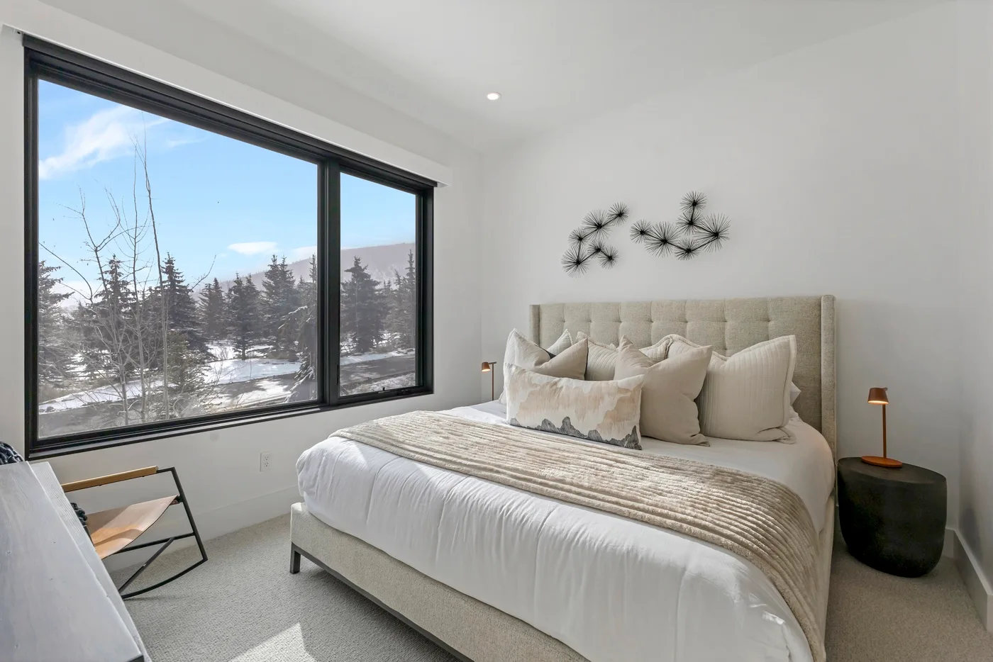 Un dormitorio luminoso con una gran ventana que da a árboles cubiertos de nieve.
