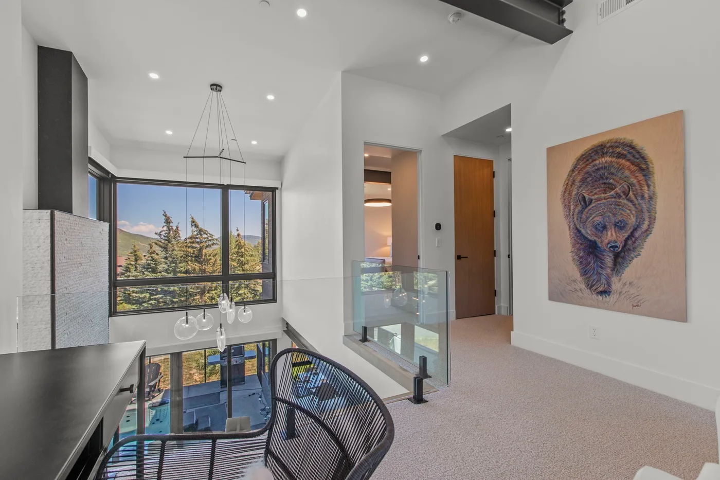 Un interior moderno y luminoso con grandes ventanas, una barandilla de vidrio y arte en la pared.