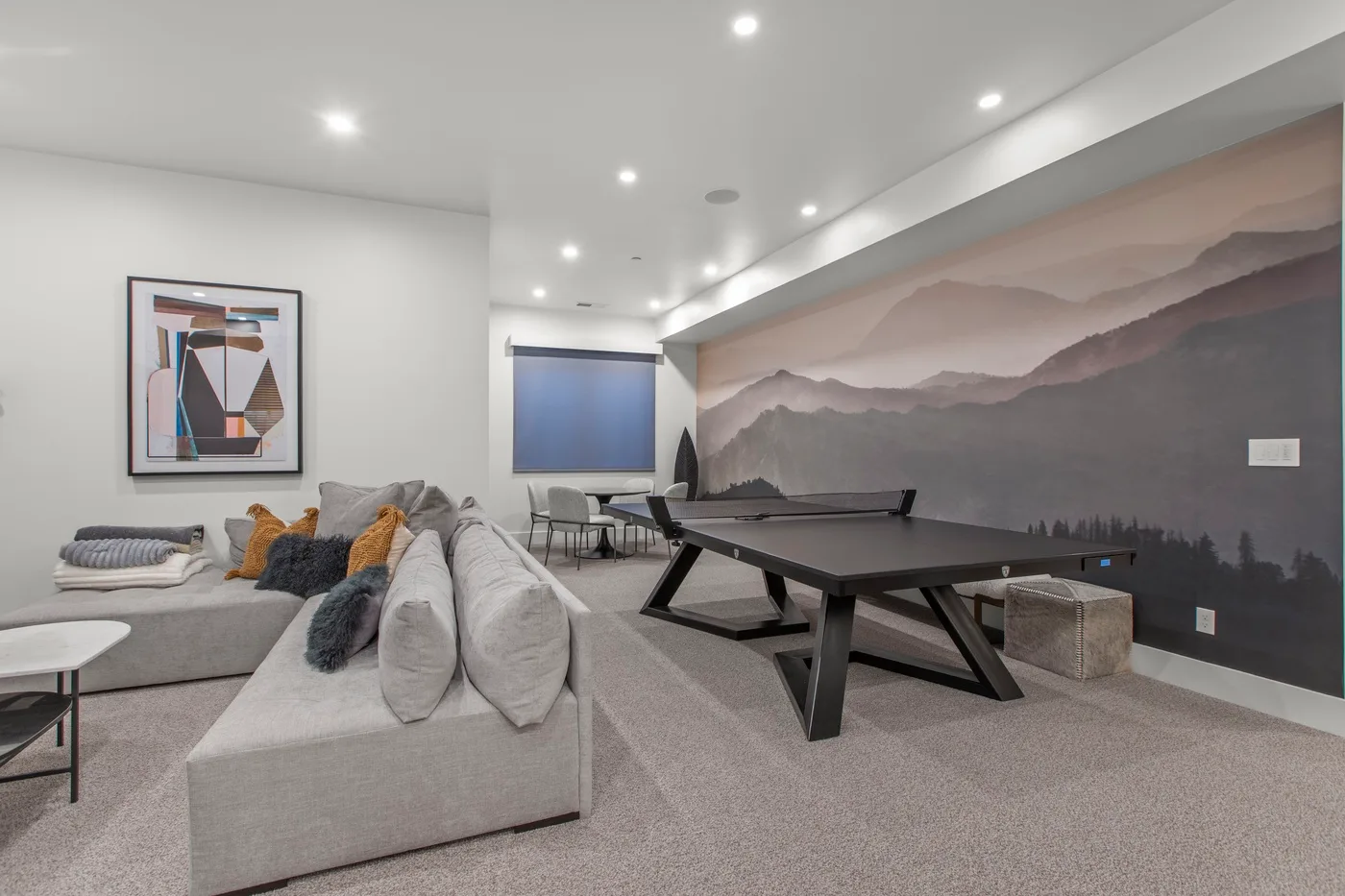 Una sala moderna con una zona de asientos seccionales y una mesa de ping-pong.