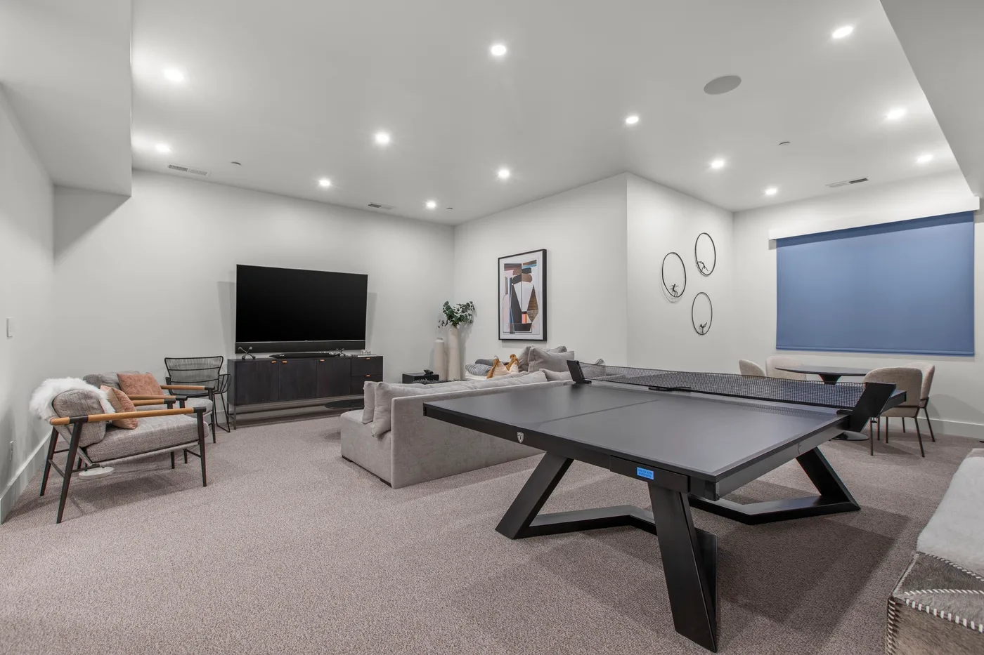 Una sala de recreación con una mesa de ping-pong, asientos y un televisor.