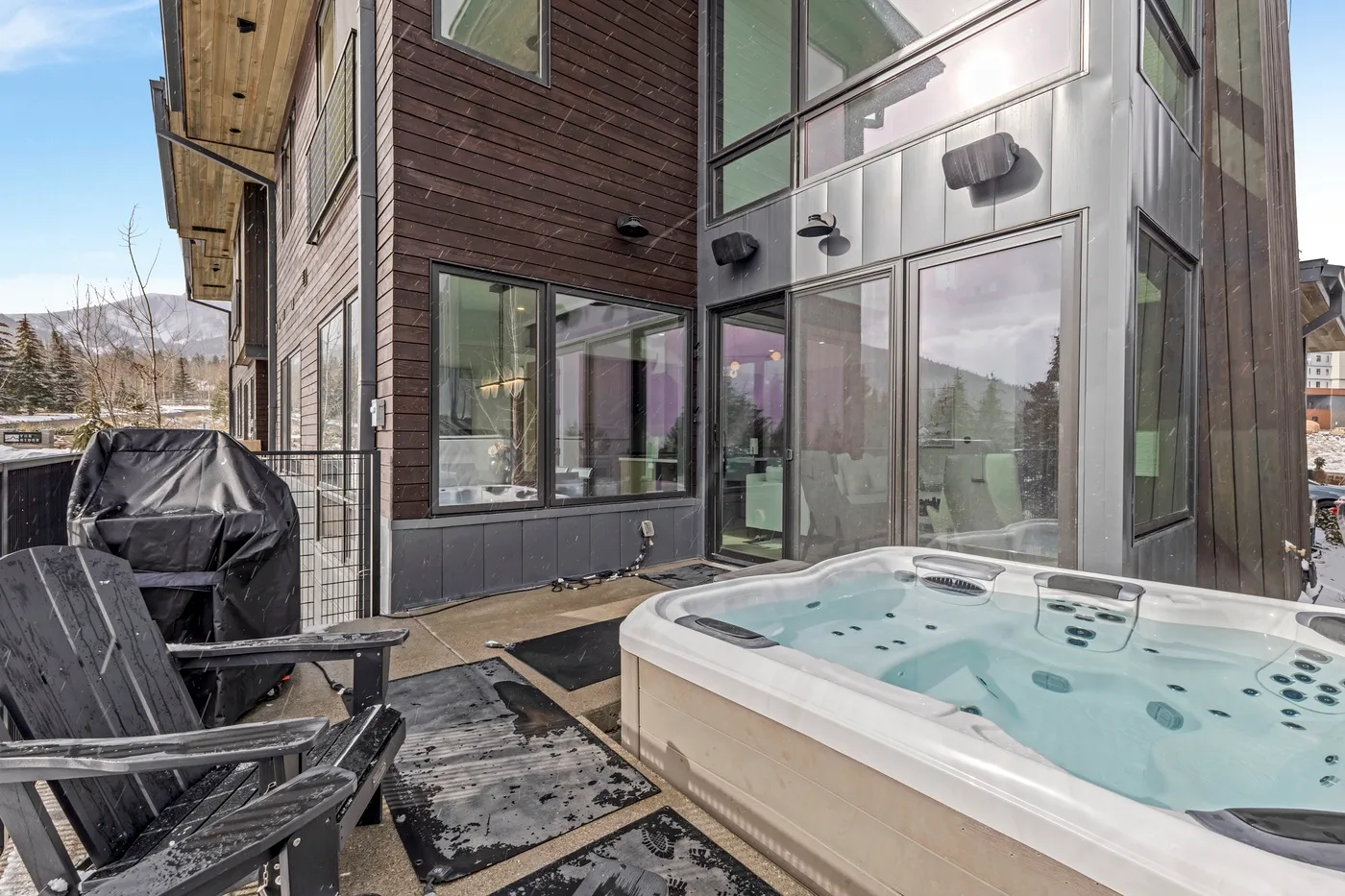 Una bañera de hidromasaje exterior está junto a un edificio moderno con grandes ventanas.