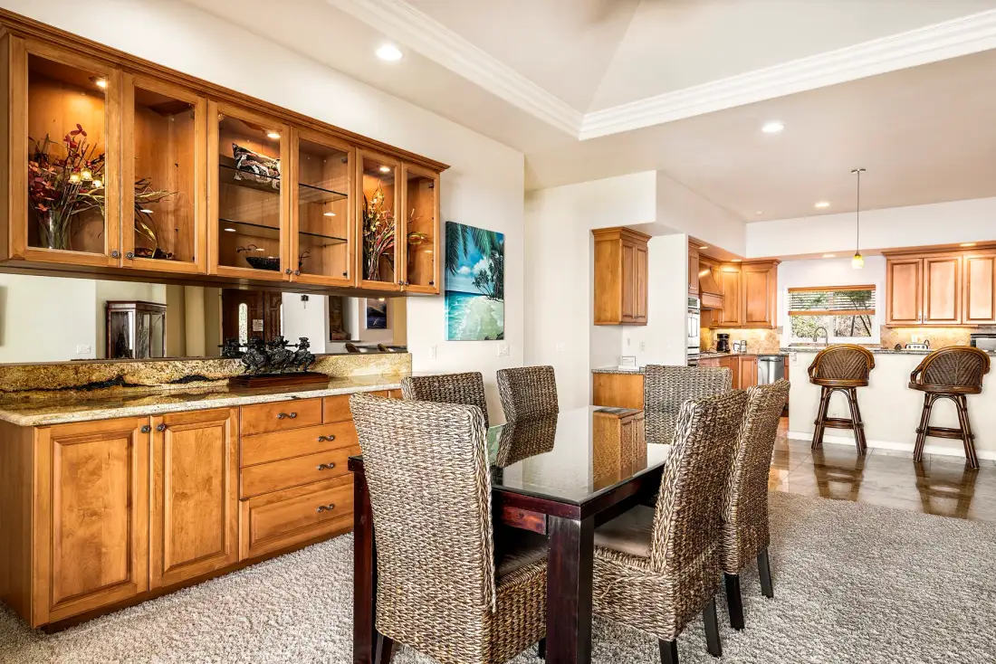 Un comedor con una mesa y asientos tejidos junto a una cocina.
