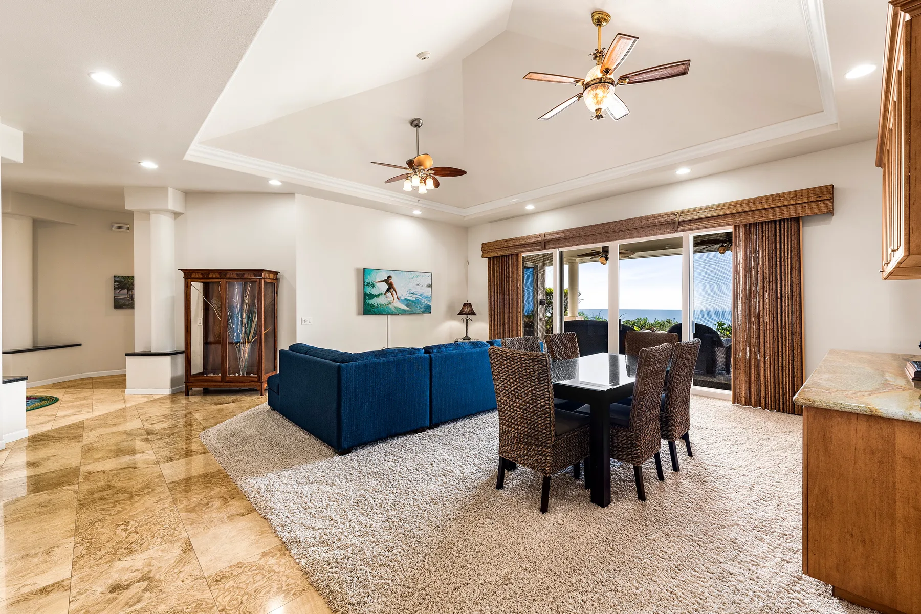 Una zona de estar y comedor con asientos azules y una mesa junto a grandes ventanas.