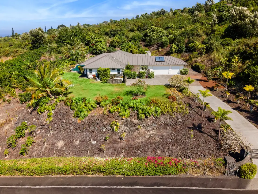 Una casa está rodeada de jardines y una entrada pavimentada.