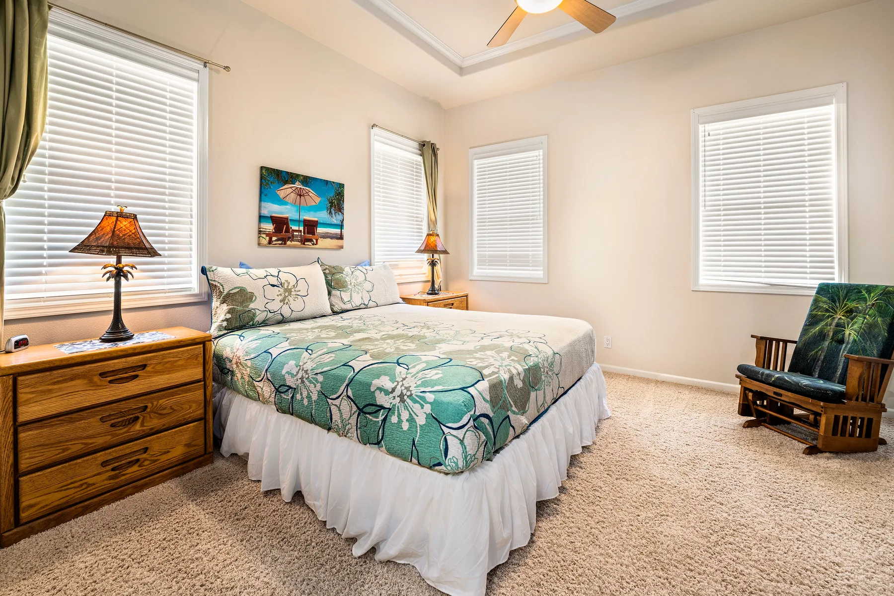 Un dormitorio con una cama, muebles auxiliares y ventanas con persianas.