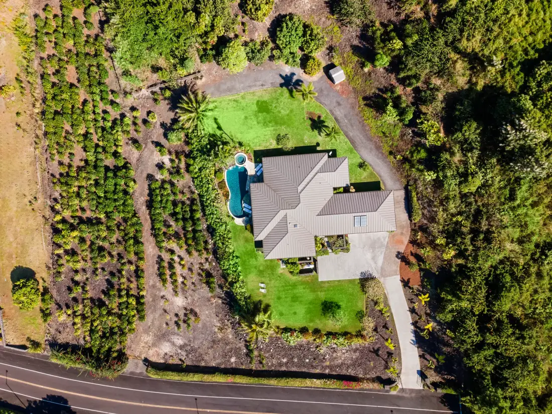 Una vista aérea muestra una casa, una piscina y vegetación alrededor.