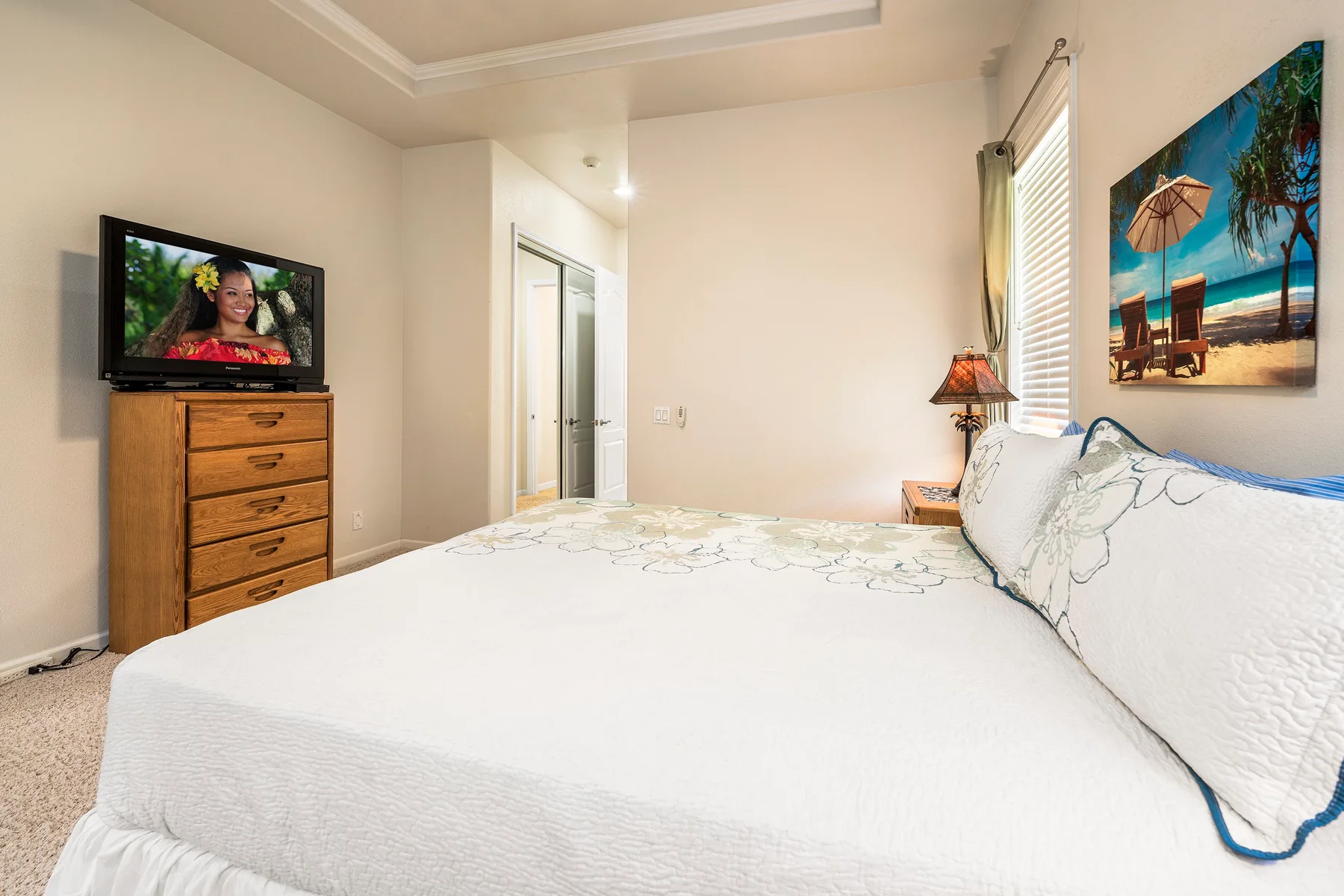 Un dormitorio con una cama grande, una cómoda y un televisor.