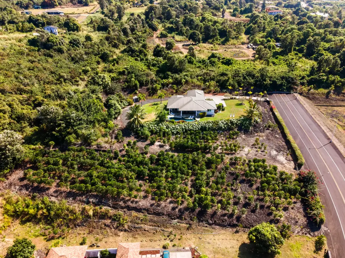Una vista aérea muestra una casa rodeada de campos verdes y árboles.