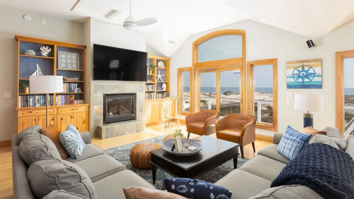 A bright living room has seating arranged around a coffee table beside large windows.