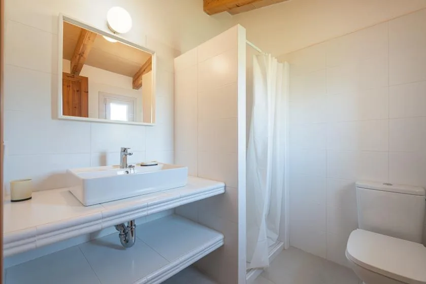 Un baño luminoso con lavabo, espejo y cortina de ducha.