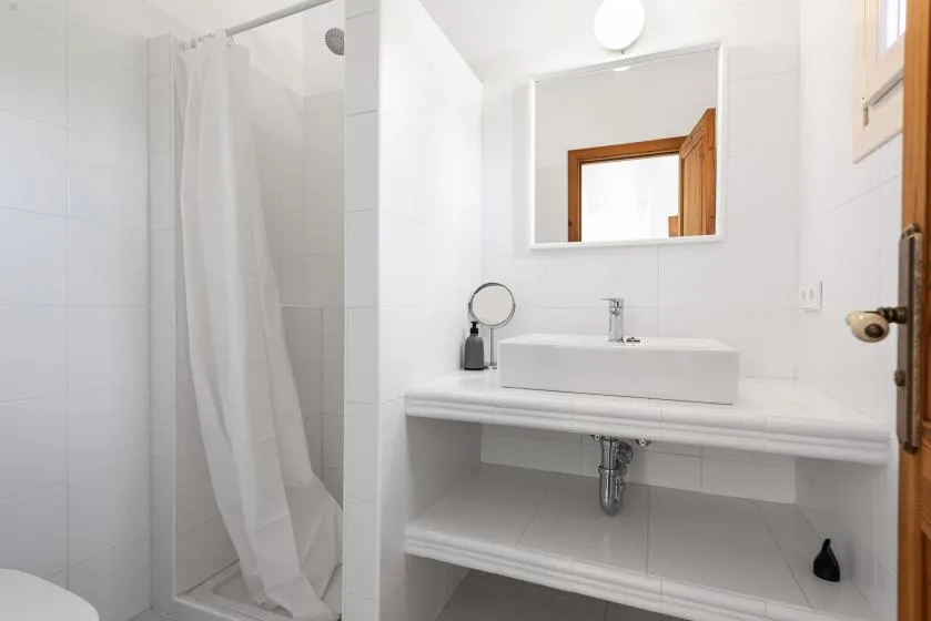 Un baño luminoso con azulejos, lavabo y cortina de ducha.