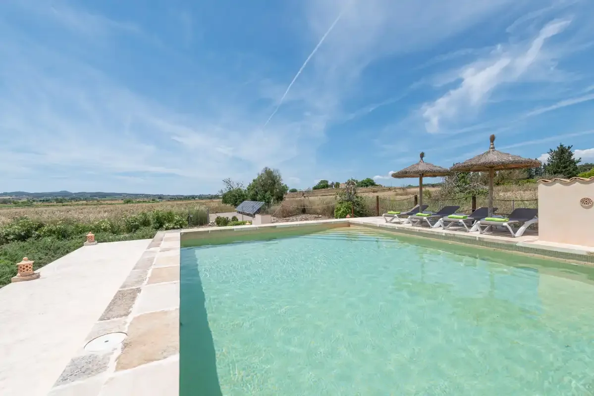 Una piscina al aire libre con tumbonas y sombrillas.