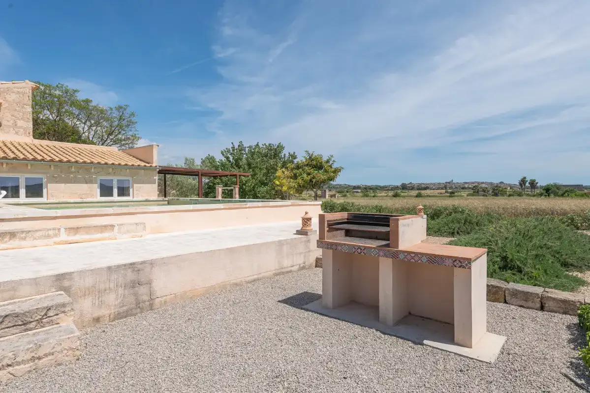 Una casa de piedra y una zona de barbacoa al aire libre dan al campo abierto.