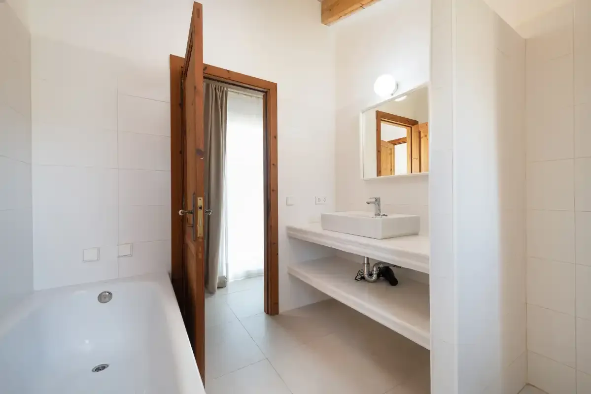 Un baño luminoso con bañera, lavabo abierto y espejo.