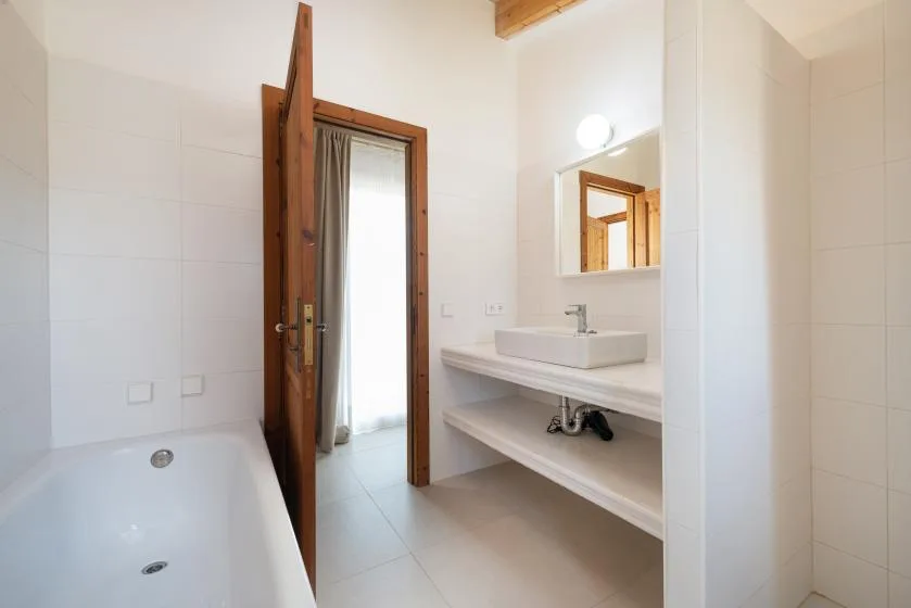 Un baño luminoso con bañera, lavabo y espejo de pared.