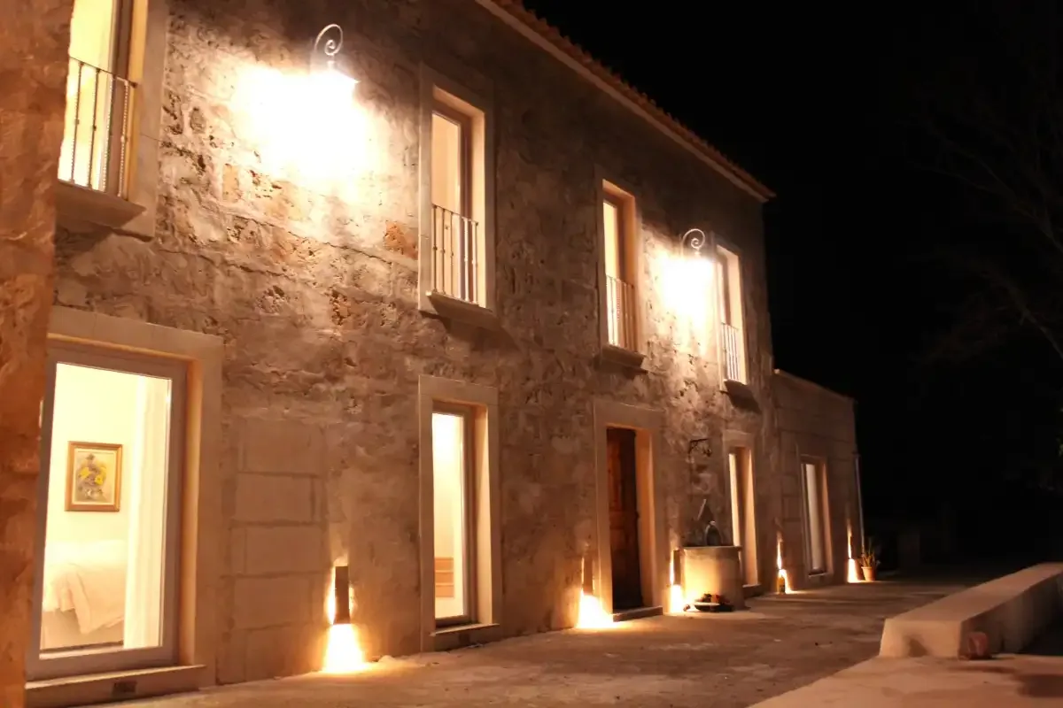 Un edificio de piedra con ventanas y puertas iluminadas por la noche.
