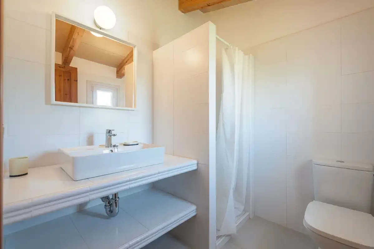 Un baño luminoso con lavabo, espejo y ducha con cortina.