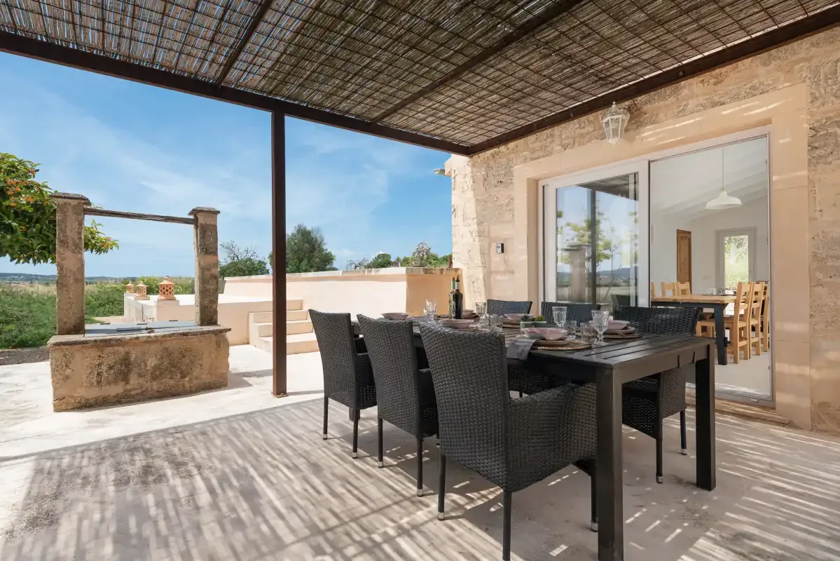 Una zona de comedor exterior cubierta con mesa y asientos junto a la casa.