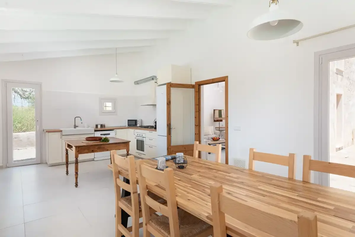 Una luminosa cocina abierta con comedor y una larga mesa de madera.