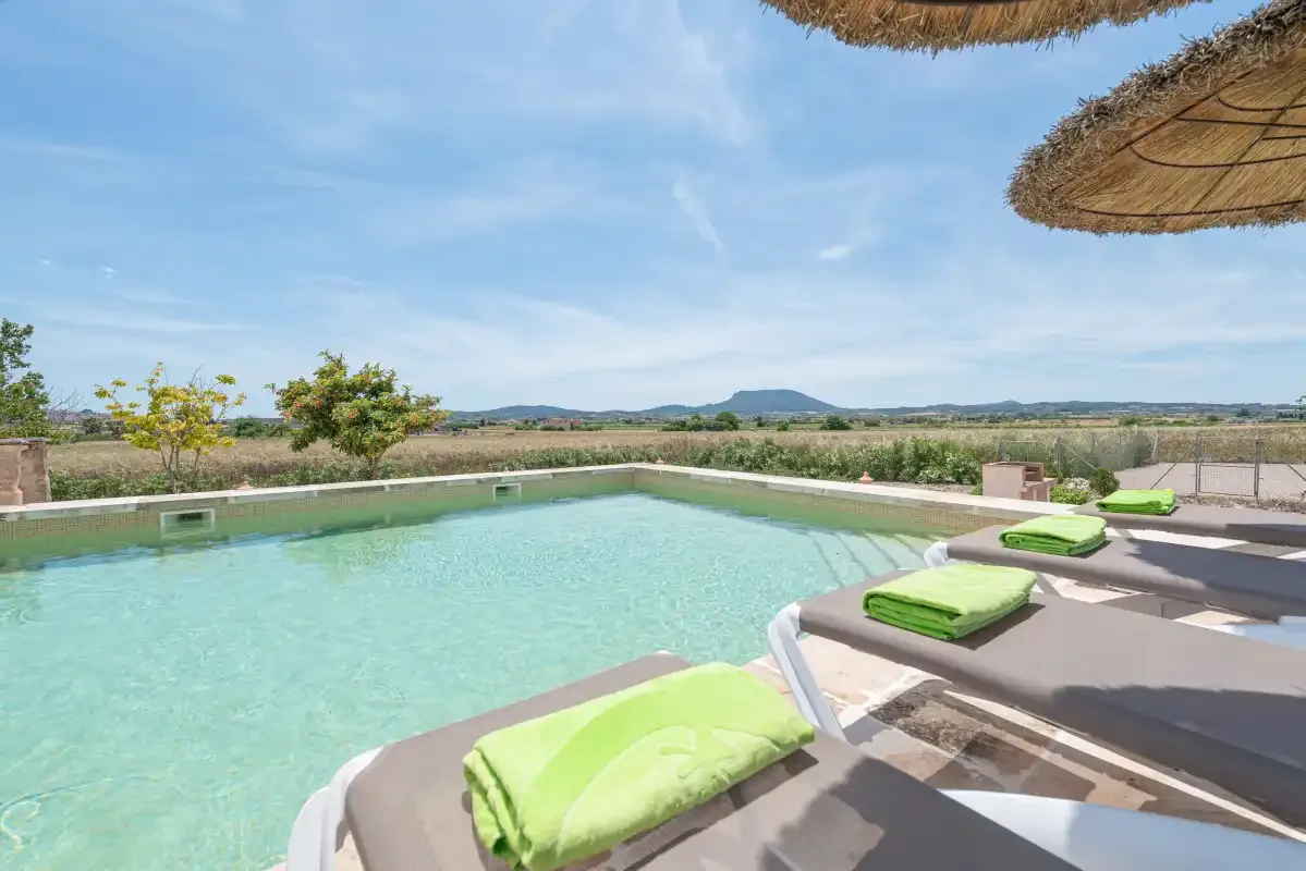 Una piscina al aire libre con tumbonas acolchadas ofrece vistas al campo circundante.