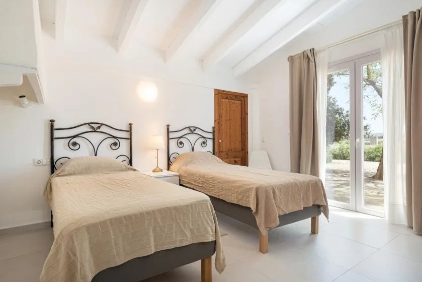 Un dormitorio luminoso con dos camas y puertas de vidrio que dan a un patio.