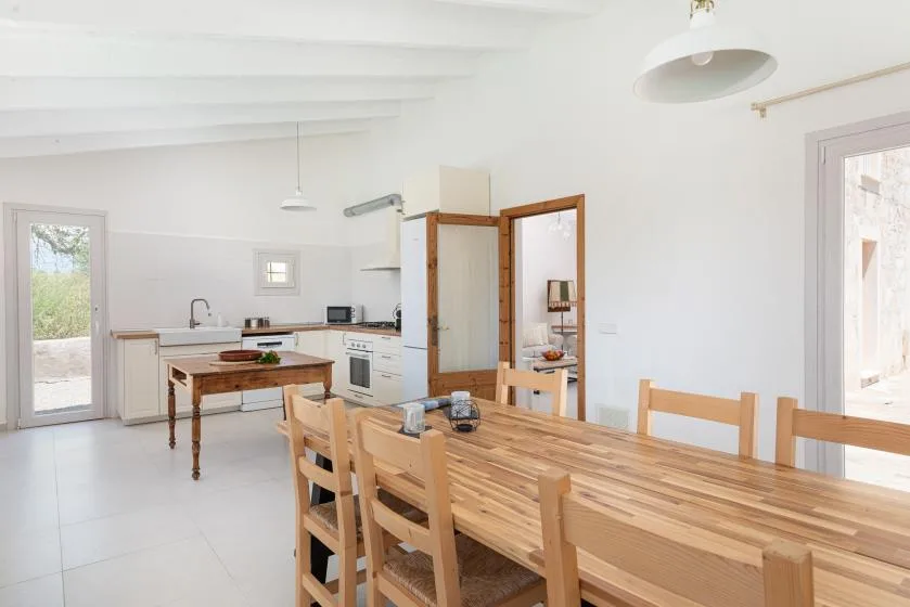 Una cocina y comedor luminosos con una mesa larga de madera y sillas.