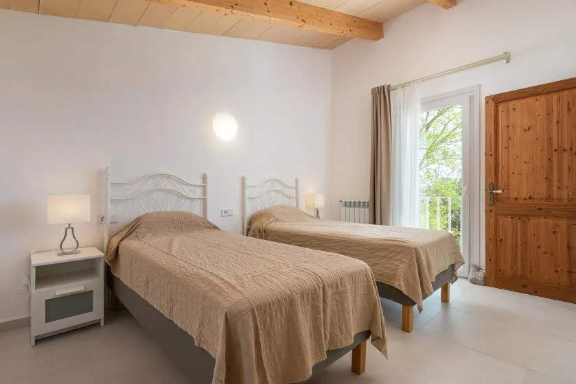 Un dormitorio con dos camas, mesitas de noche y una puerta acristalada que da a un balcón.