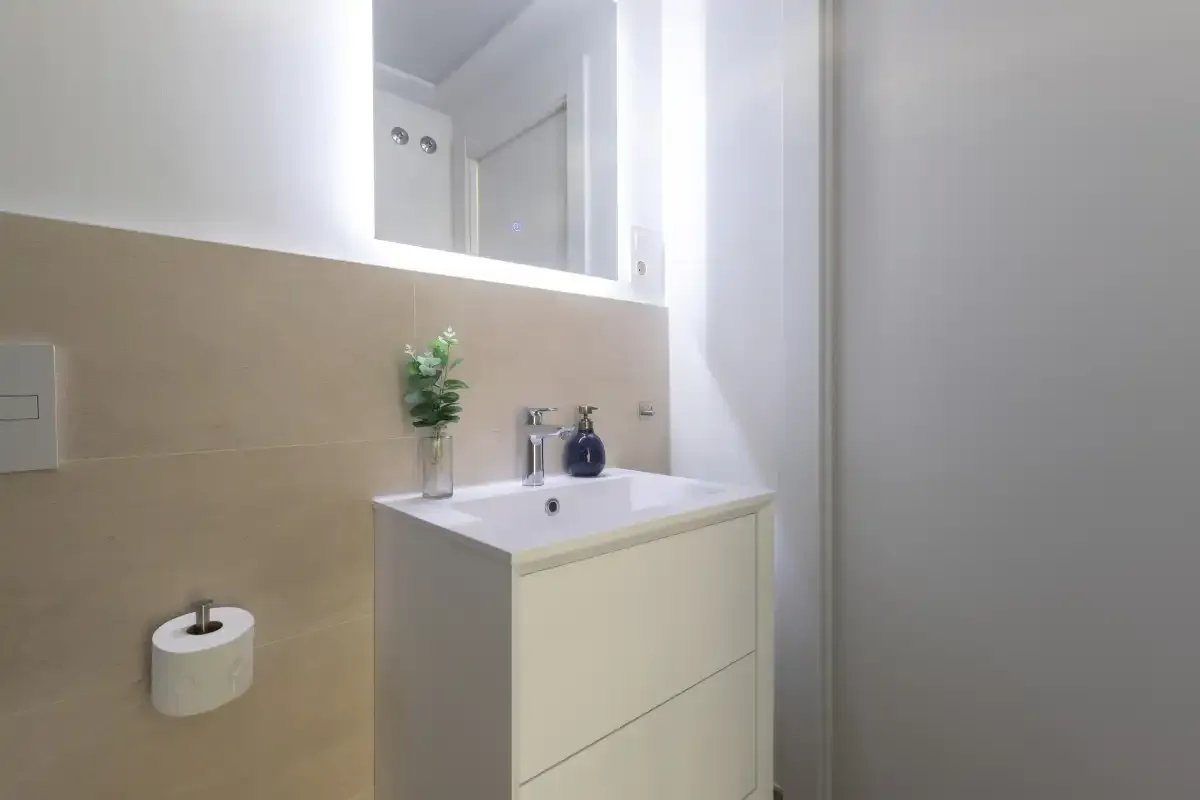 Lavabo de baño con fregadero, grifo y espejo.