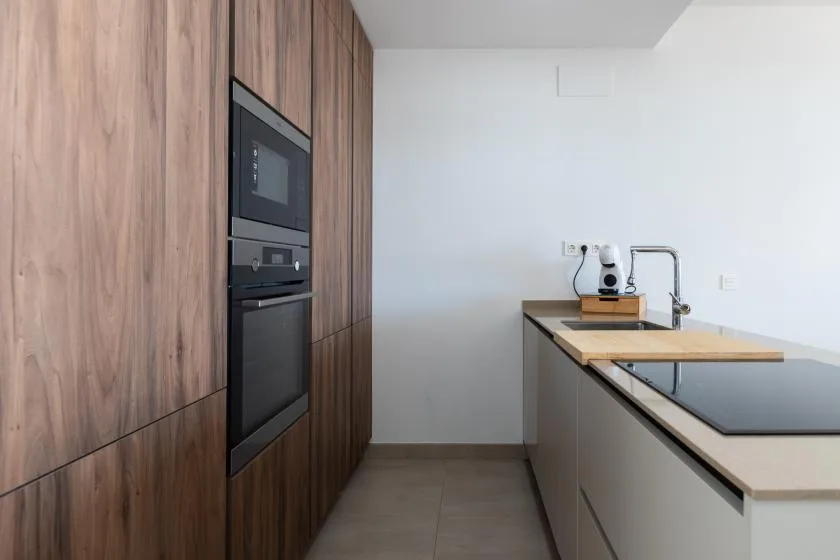 Una cocina moderna con gabinetes de madera y una isla larga con placa de cocción.