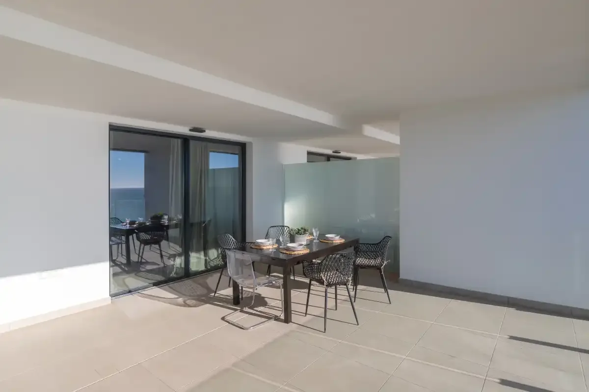 Una zona cubierta para comer da a un balcón con vistas al mar.