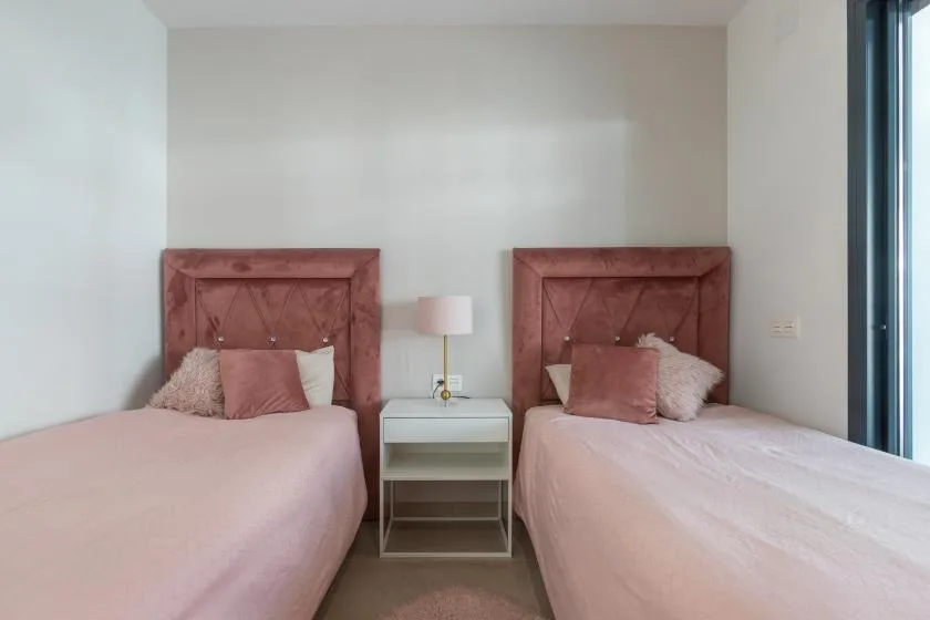 Un dormitorio con dos camas y una mesita entre ellas.