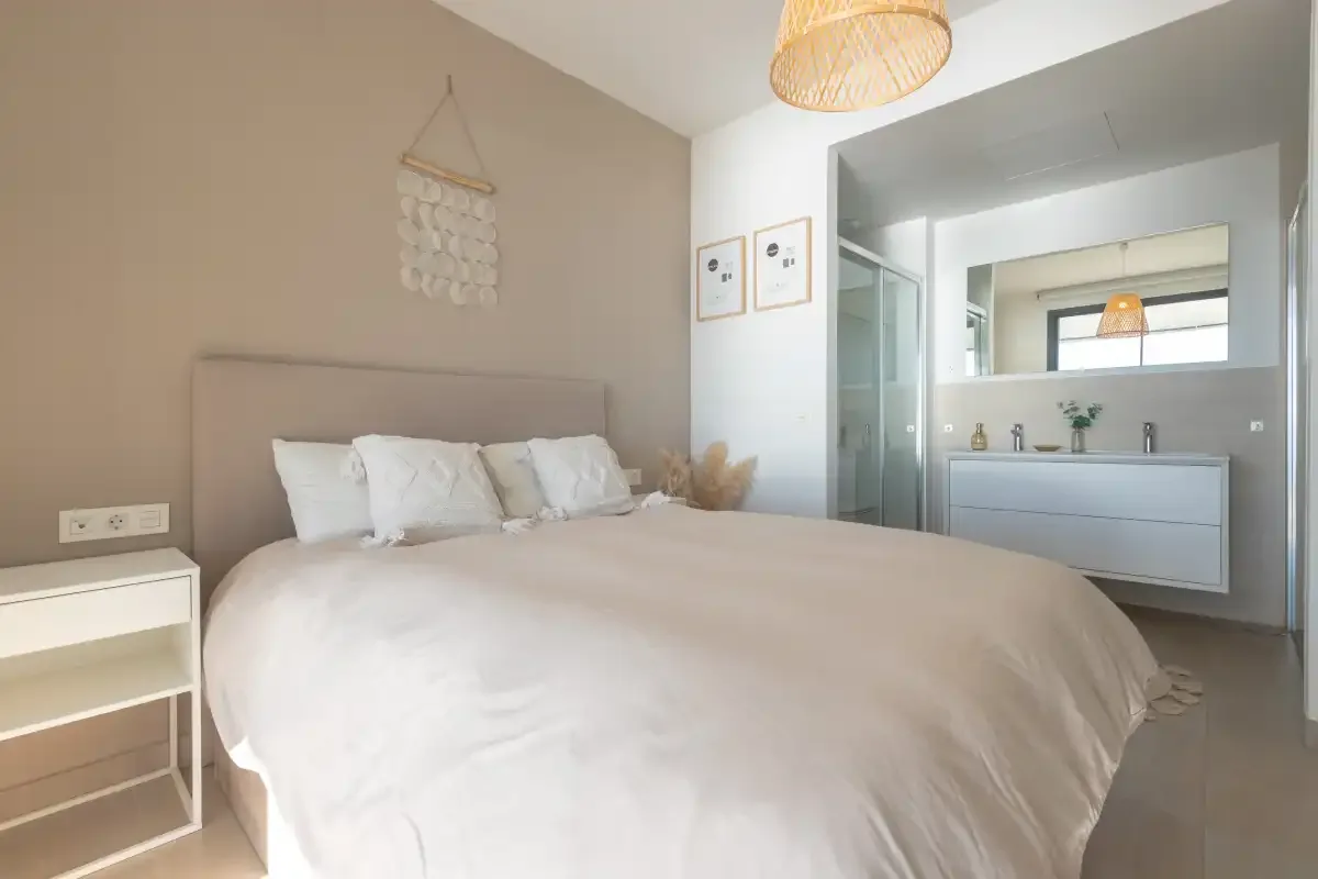 Un dormitorio con una cama grande y un tocador de baño contiguo.