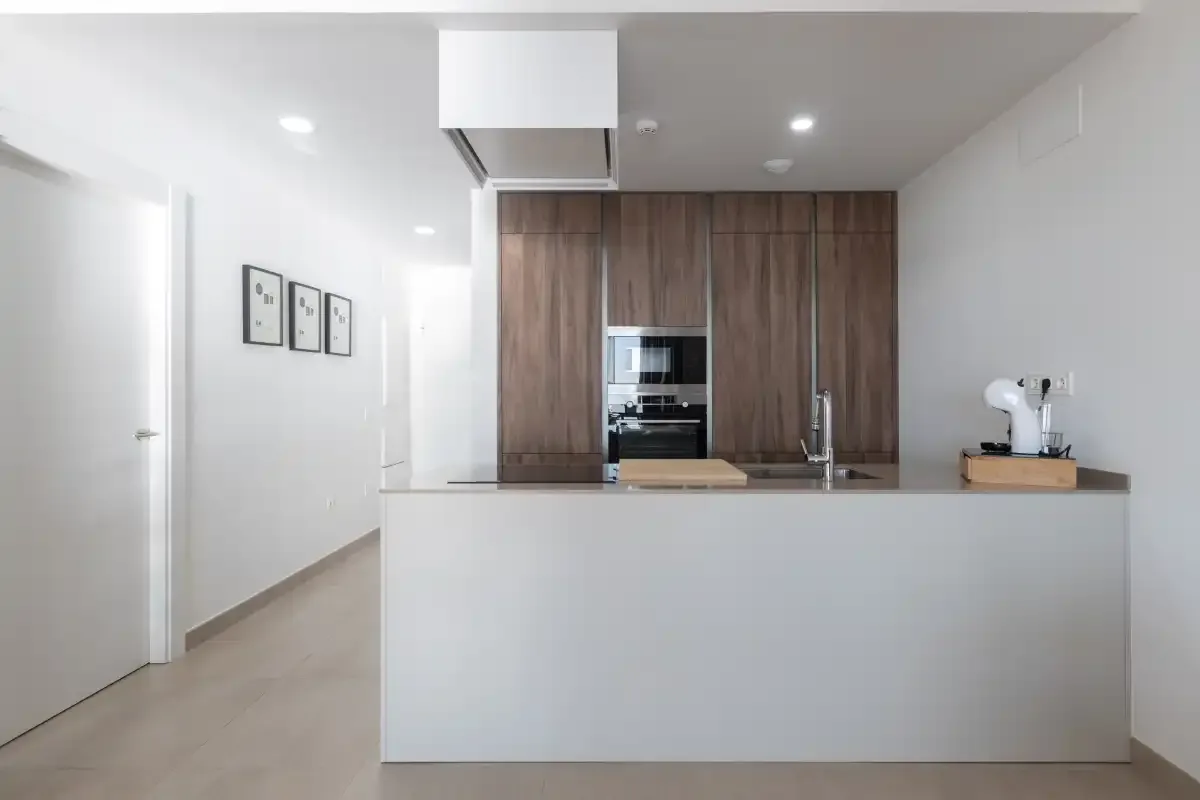 Una cocina moderna con armarios de madera y una isla blanca.
