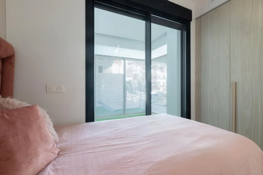 Dormitorio con una cama junto a grandes puertas corredizas de vidrio.