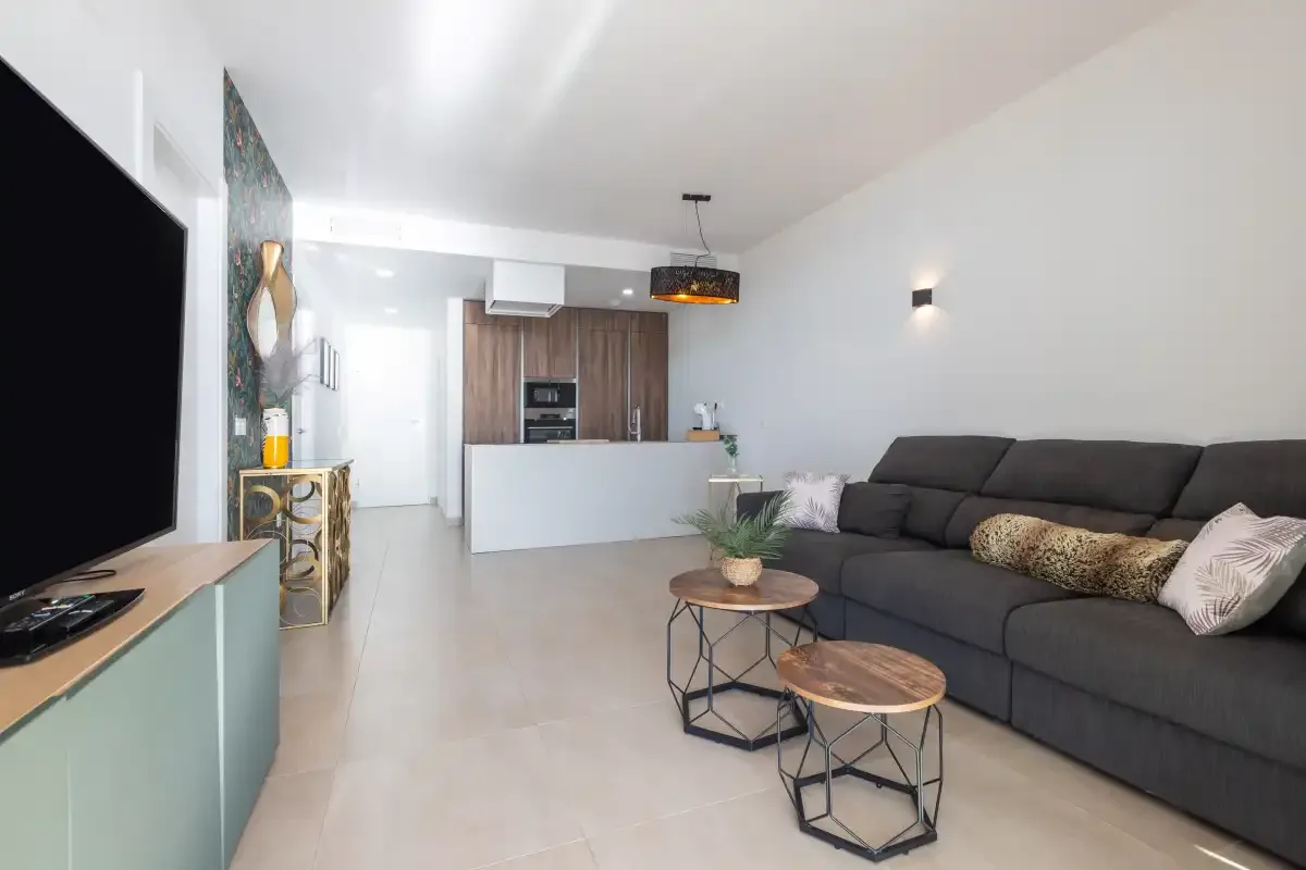 Una sala de estar moderna con un sofá amplio y una cocina abierta.