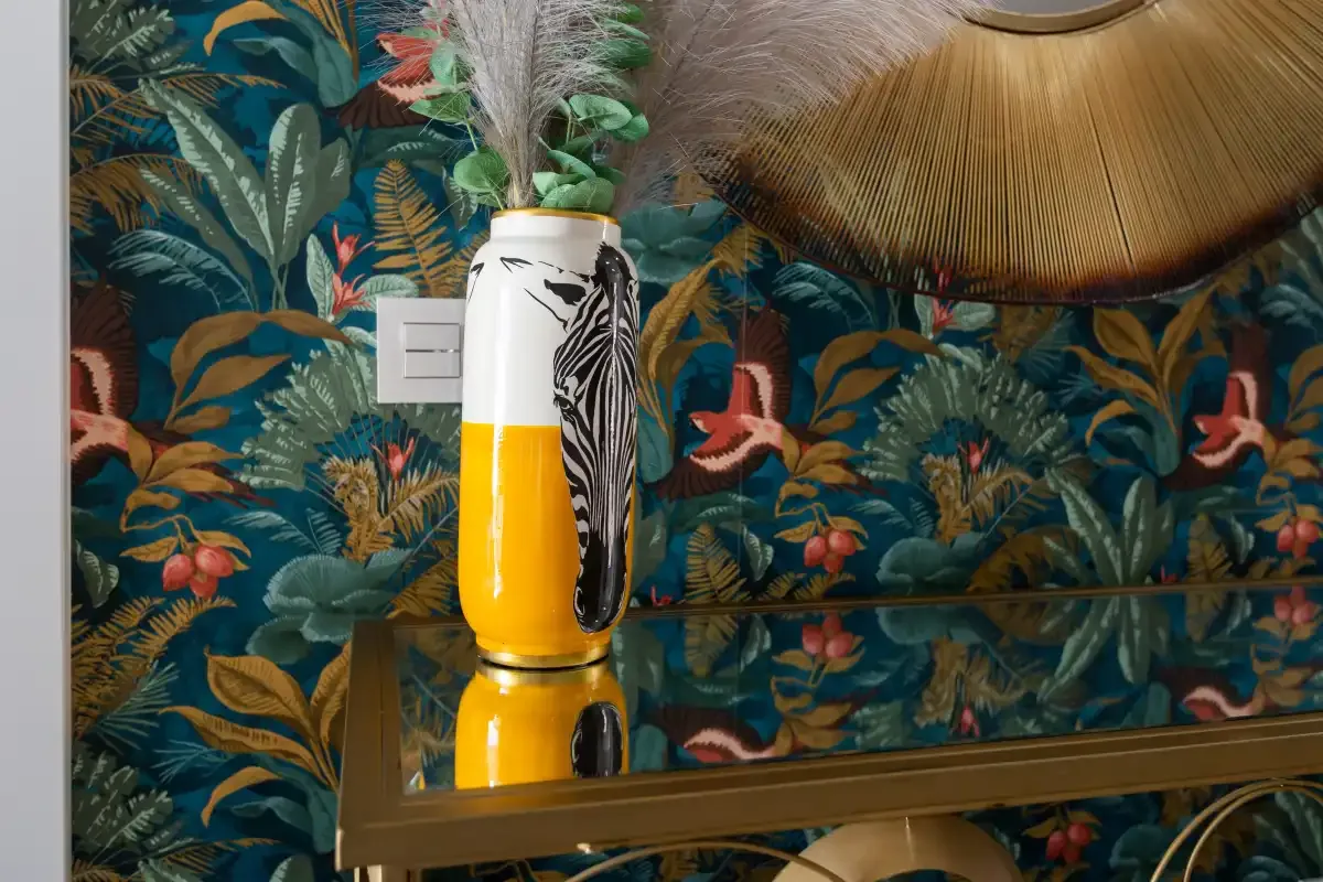 Una mesa decorativa con un jarrón estampado y una lámpara colgante de tejido.