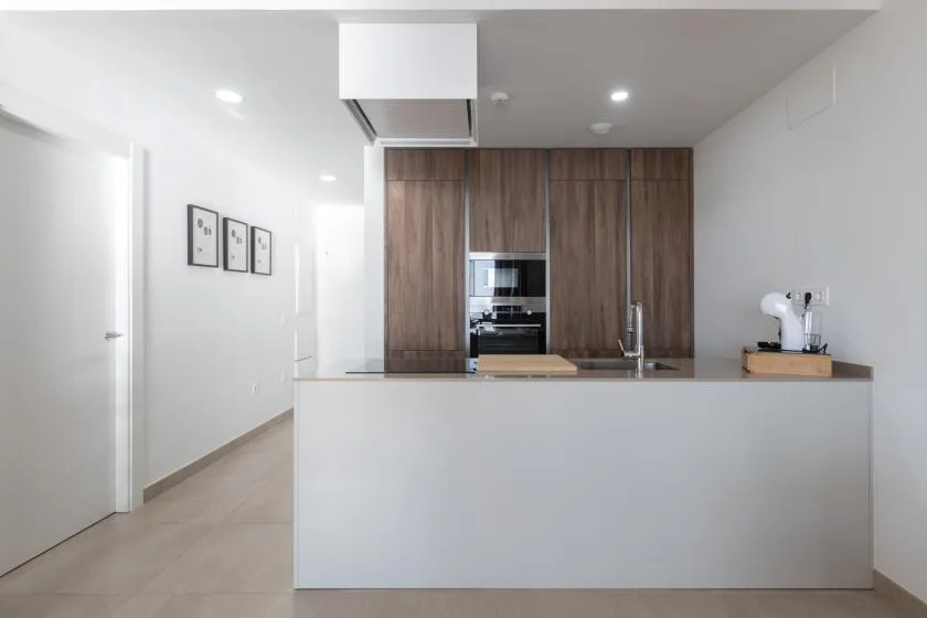 Una cocina moderna con una isla central y gabinetes de madera oscura.