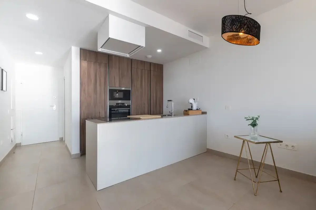 Una cocina moderna con una isla blanca y gabinetes de madera.