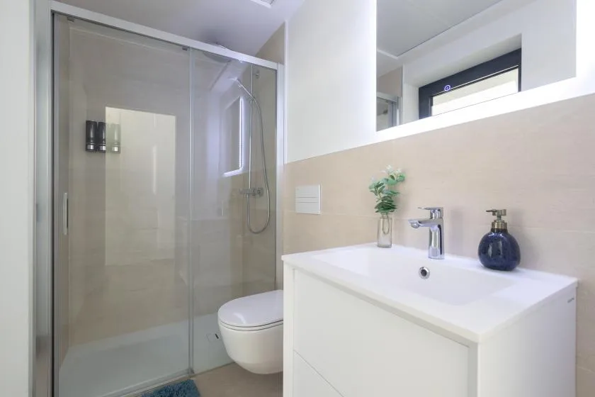 Un baño moderno con una ducha de vidrio y un lavabo blanco.