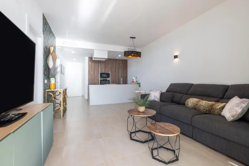 Sala de estar y cocina de concepto abierto, con asientos oscuros e isla de cocina blanca.